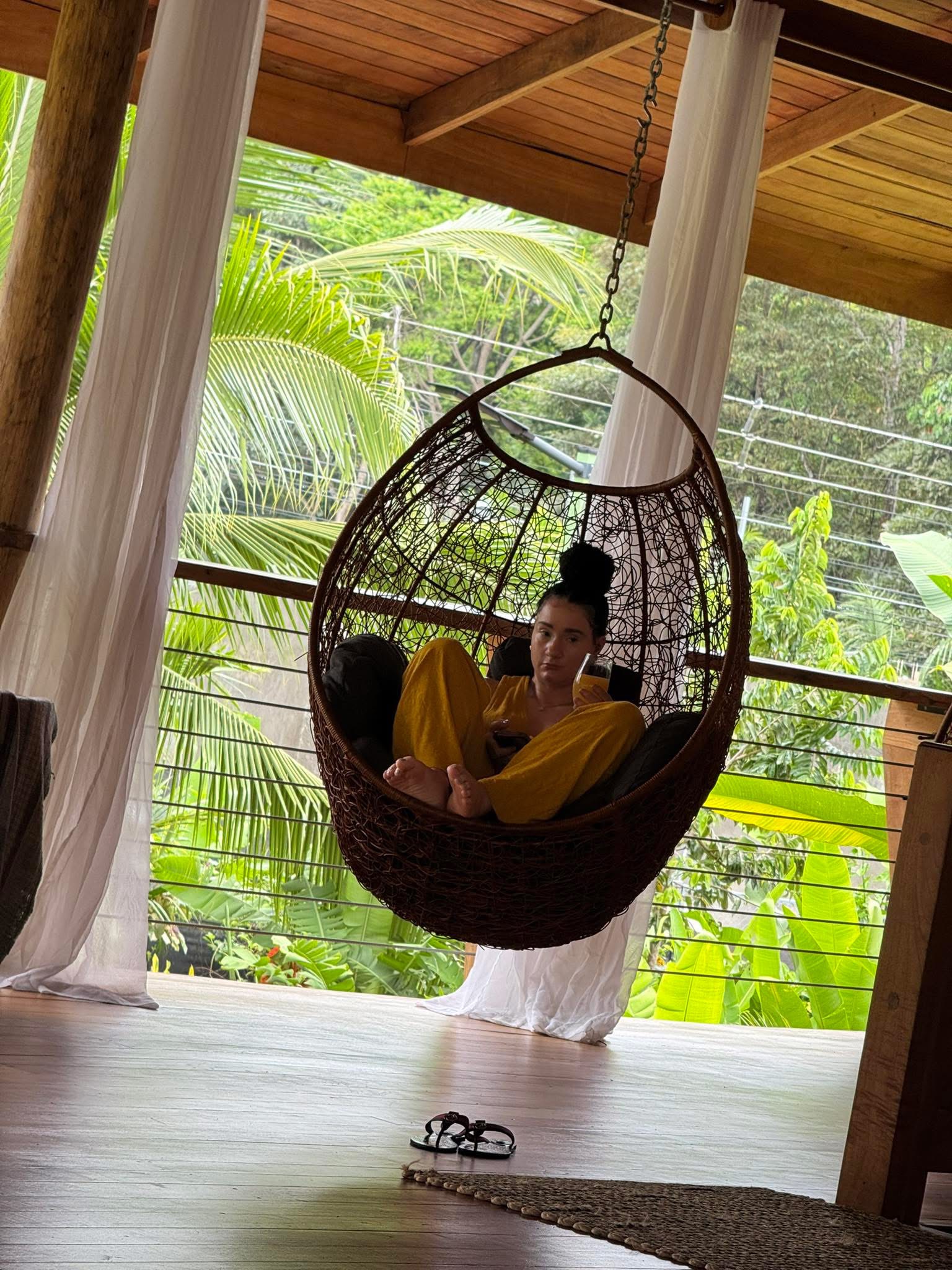 Woman relaxing in a hanging chair on a tropical Costa Rica veranda surrounded by jungle